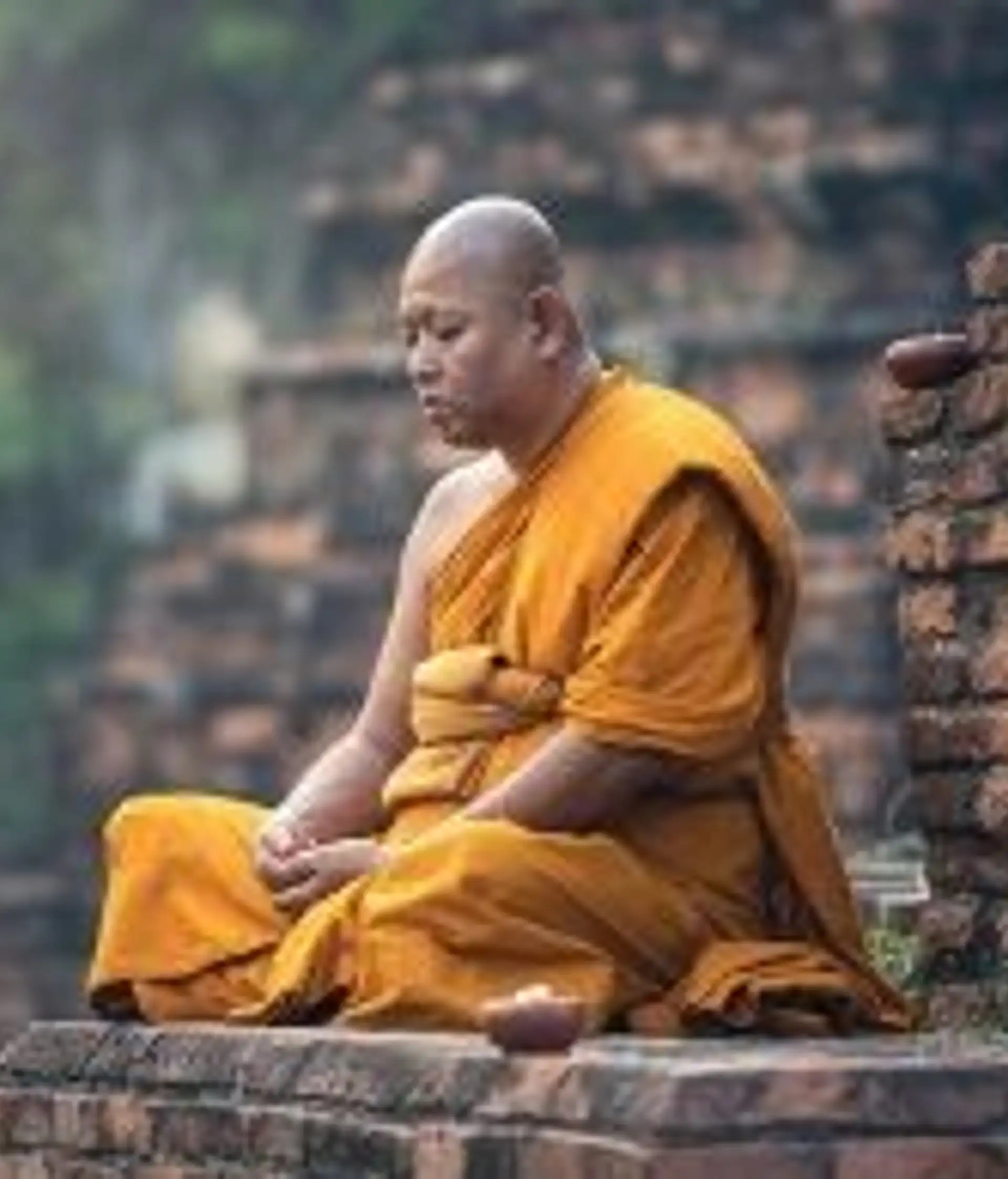 Travel in Asia - A Buddhist monk sitting cross-legged on a temple grounds in meditation in Myanmar
