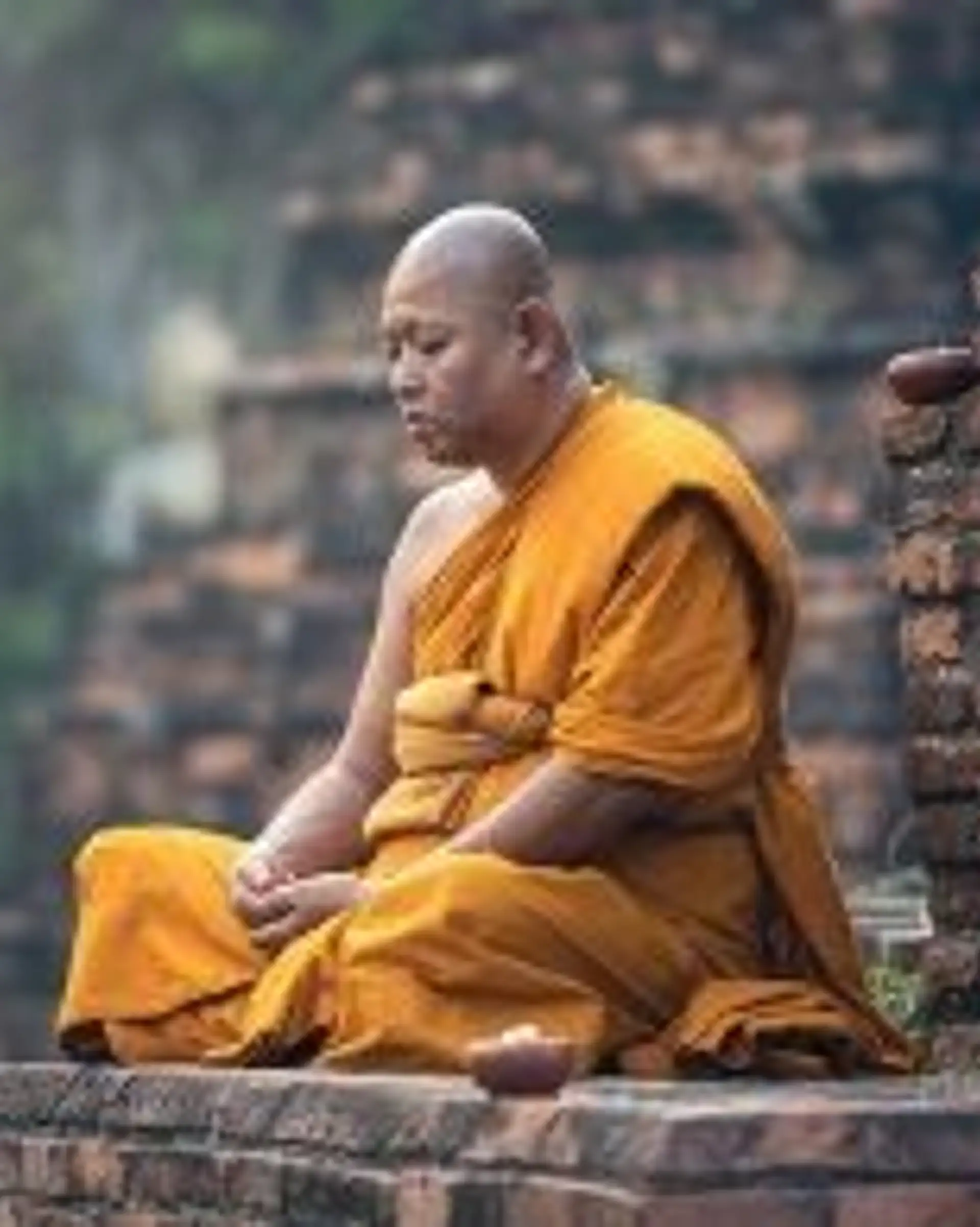 Travel in Asia - A Buddhist monk sitting cross-legged on a temple grounds in meditation in Myanmar