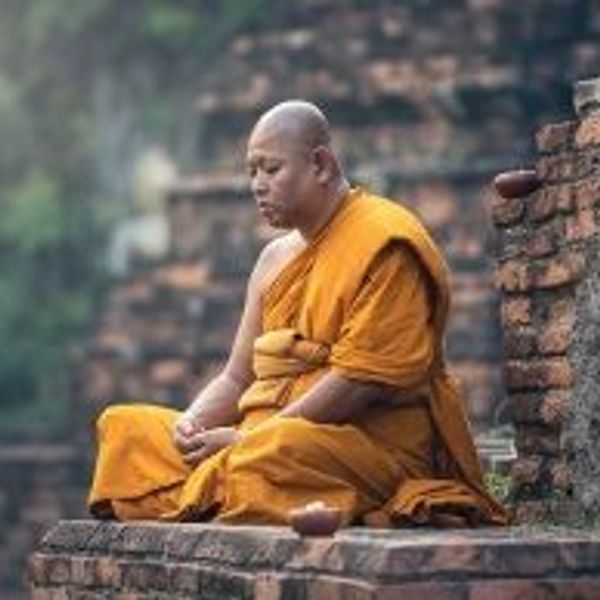 Travel in Asia - A Buddhist monk sitting cross-legged on a temple grounds in meditation in Myanmar