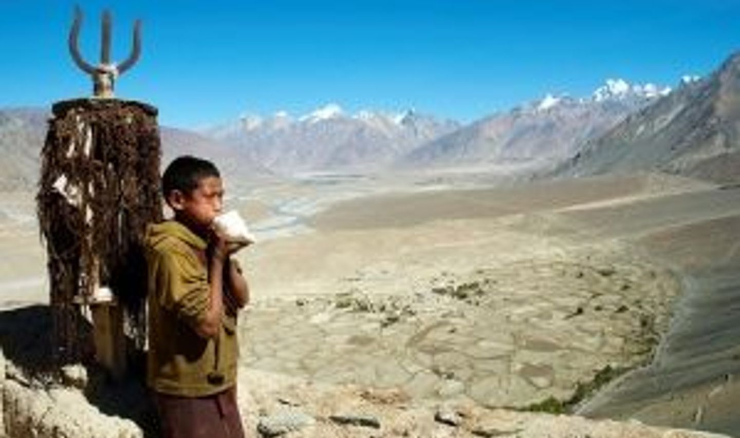 Travel in Asia - A young boy standing in front of the vast highlands near the Karsha Gompa monastery in Zanskar, Ladakh in India