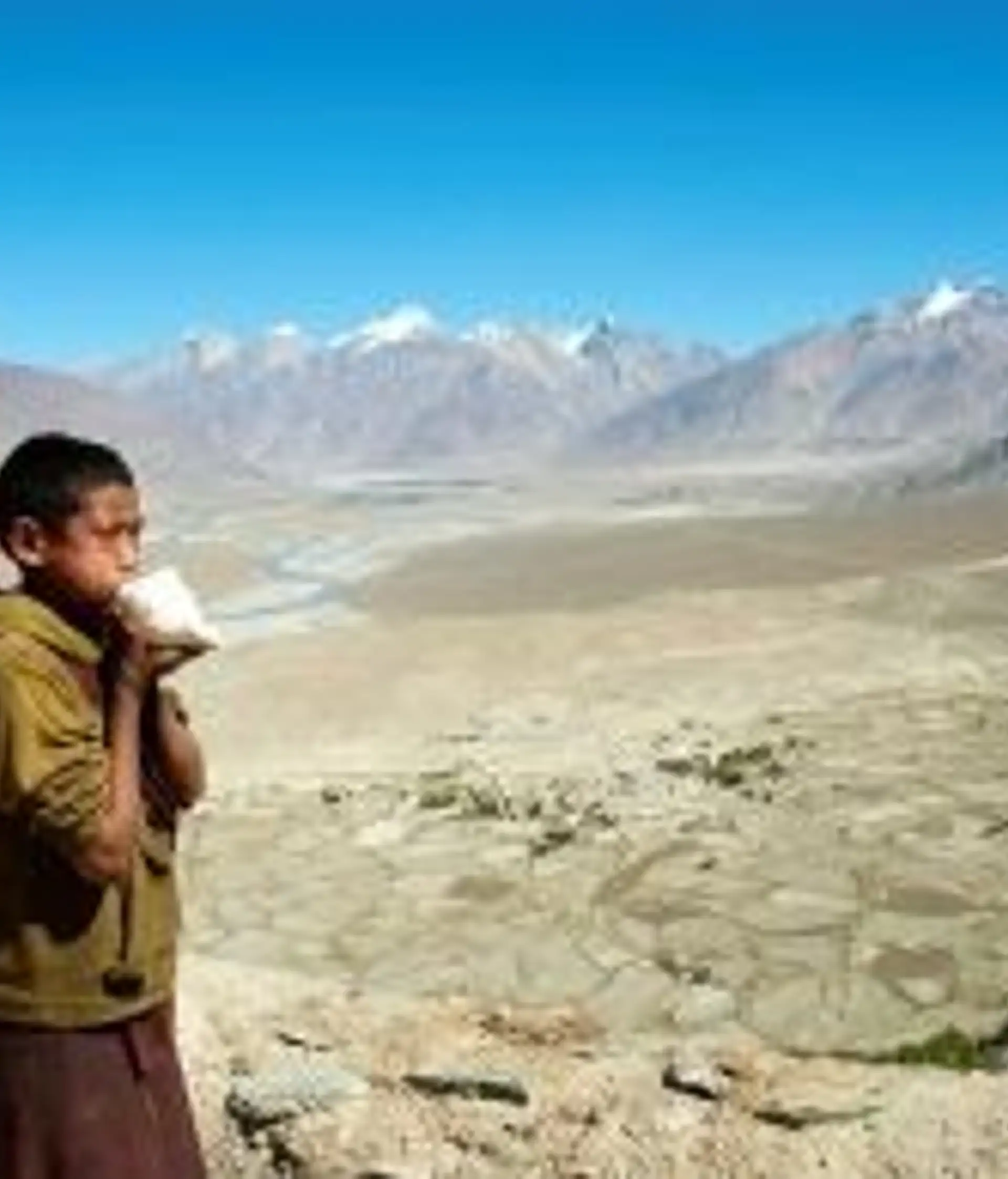 Travel in Asia - A young boy standing in front of the vast highlands near the Karsha Gompa monastery in Zanskar, Ladakh in India
