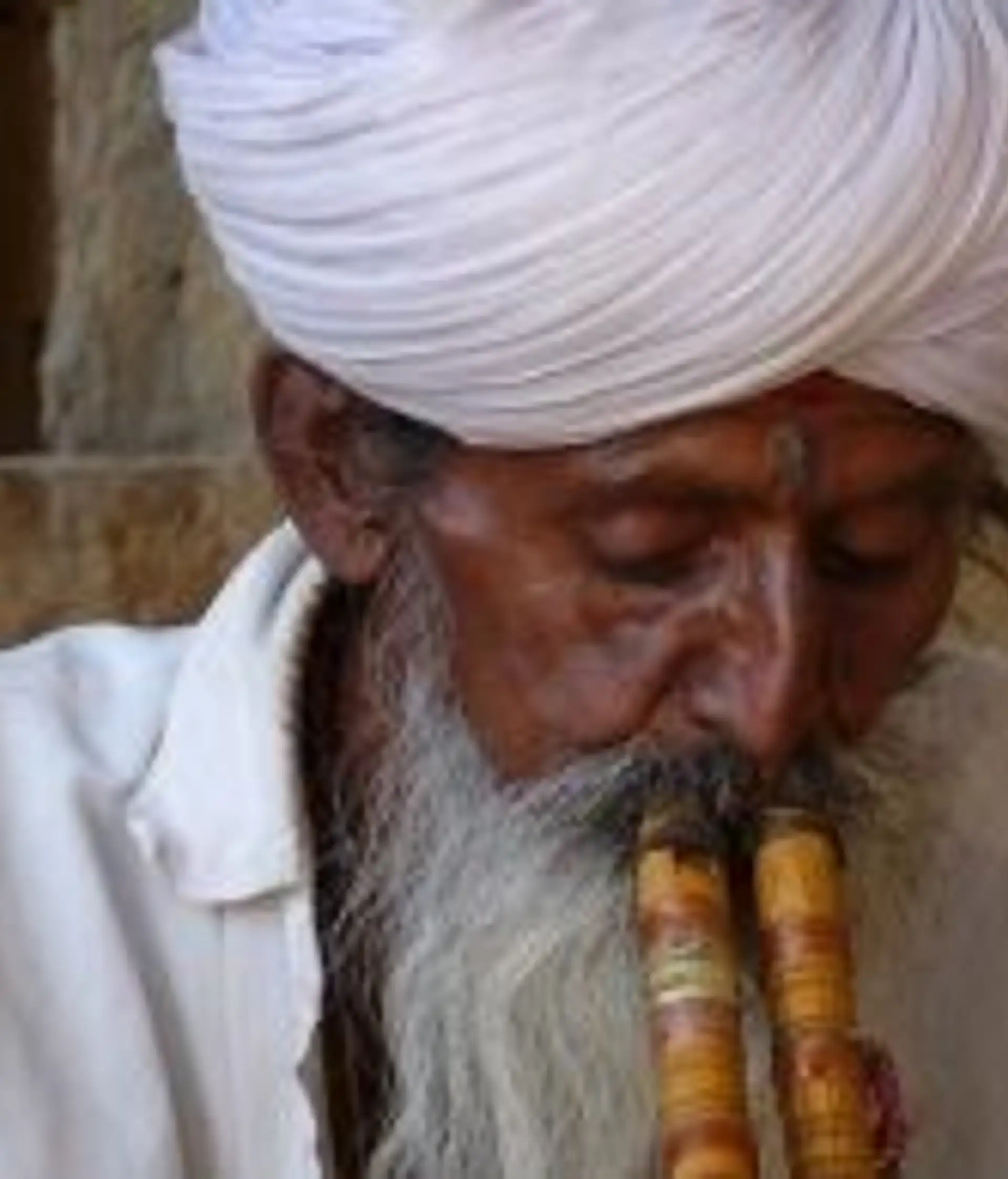 Travel in Asia - An elderly man wearing a white turban playing a donali in South India