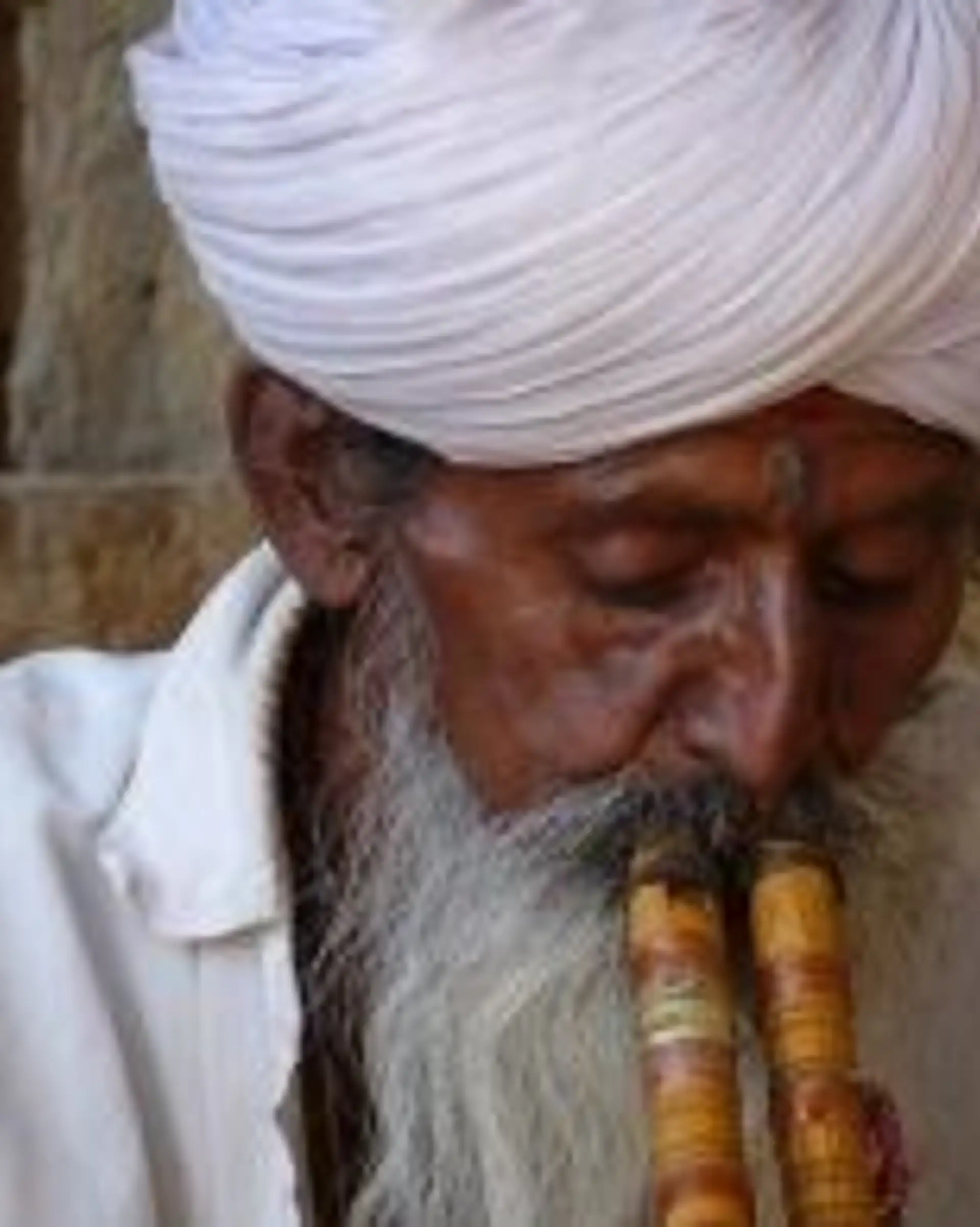 Travel in Asia - An elderly man wearing a white turban playing a donali in South India