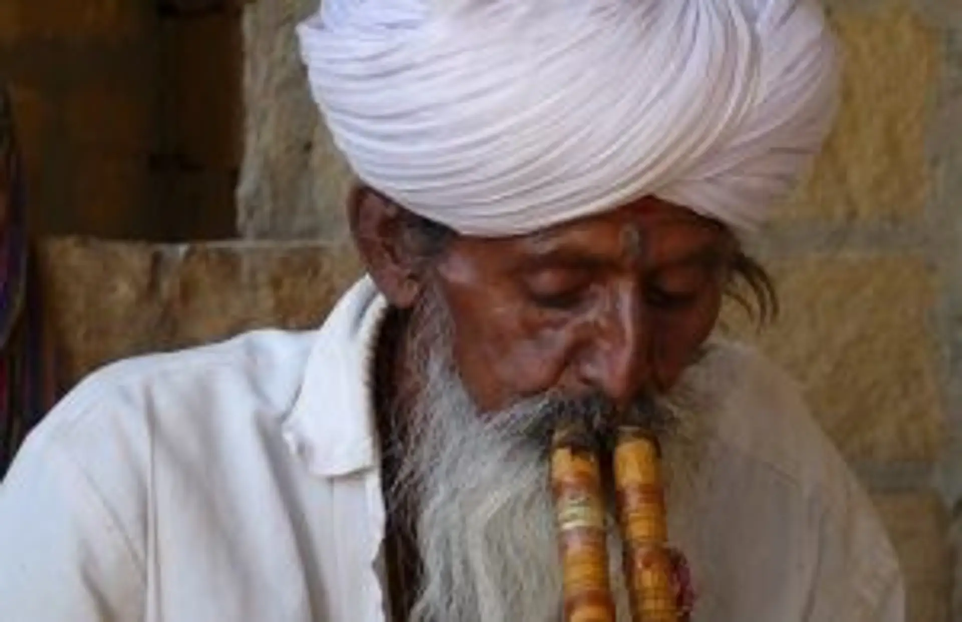 Travel in Asia - An elderly man wearing a white turban playing a donali in South India