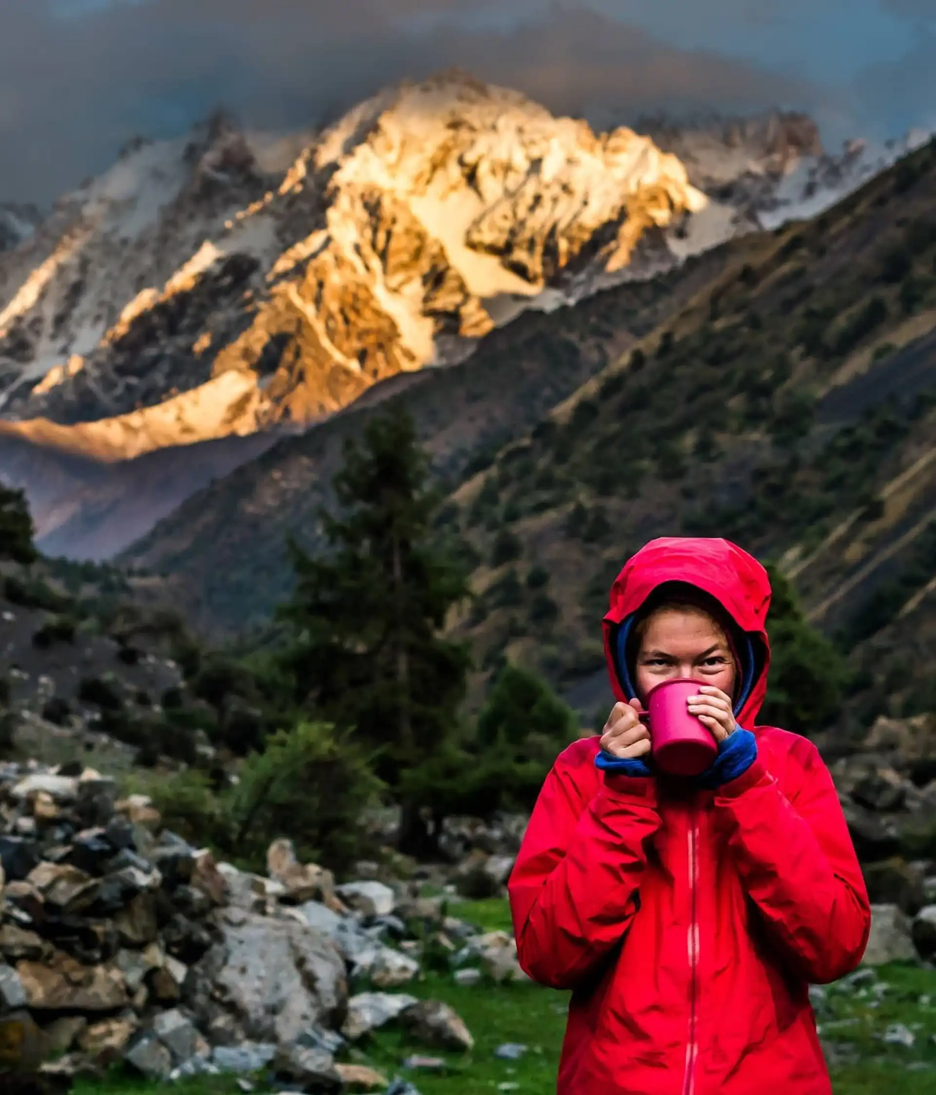 Un voyageur en veste rouge contemple des sommets montagneux majestueux lors d'une aventure au cœur de l'Asie centrale en Ouzbékistan.