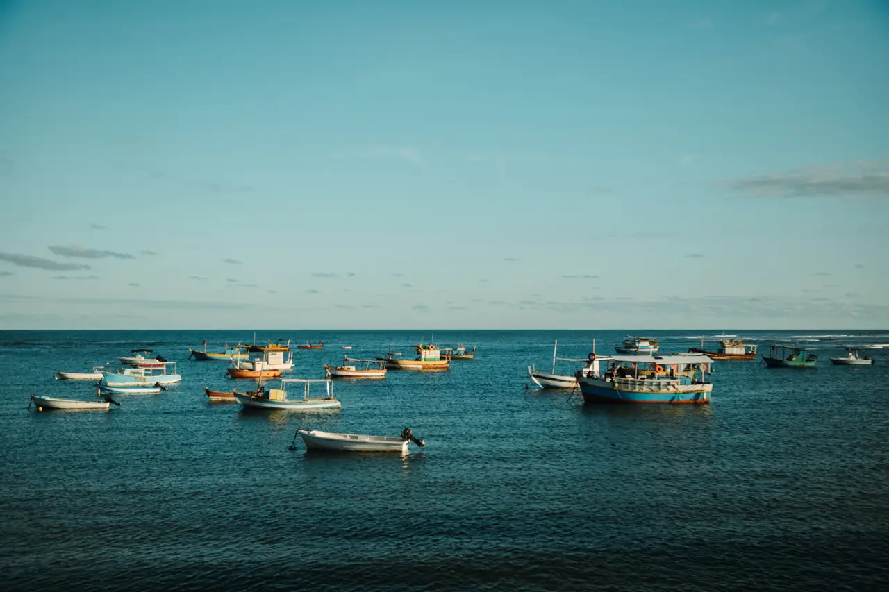 Voyage au Brésil – Alignement de bateaux de pêcheurs traditionnels amarrés sur les eaux calmes et turquoise de Praia do Forte, sur le littoral nord de Bahia.