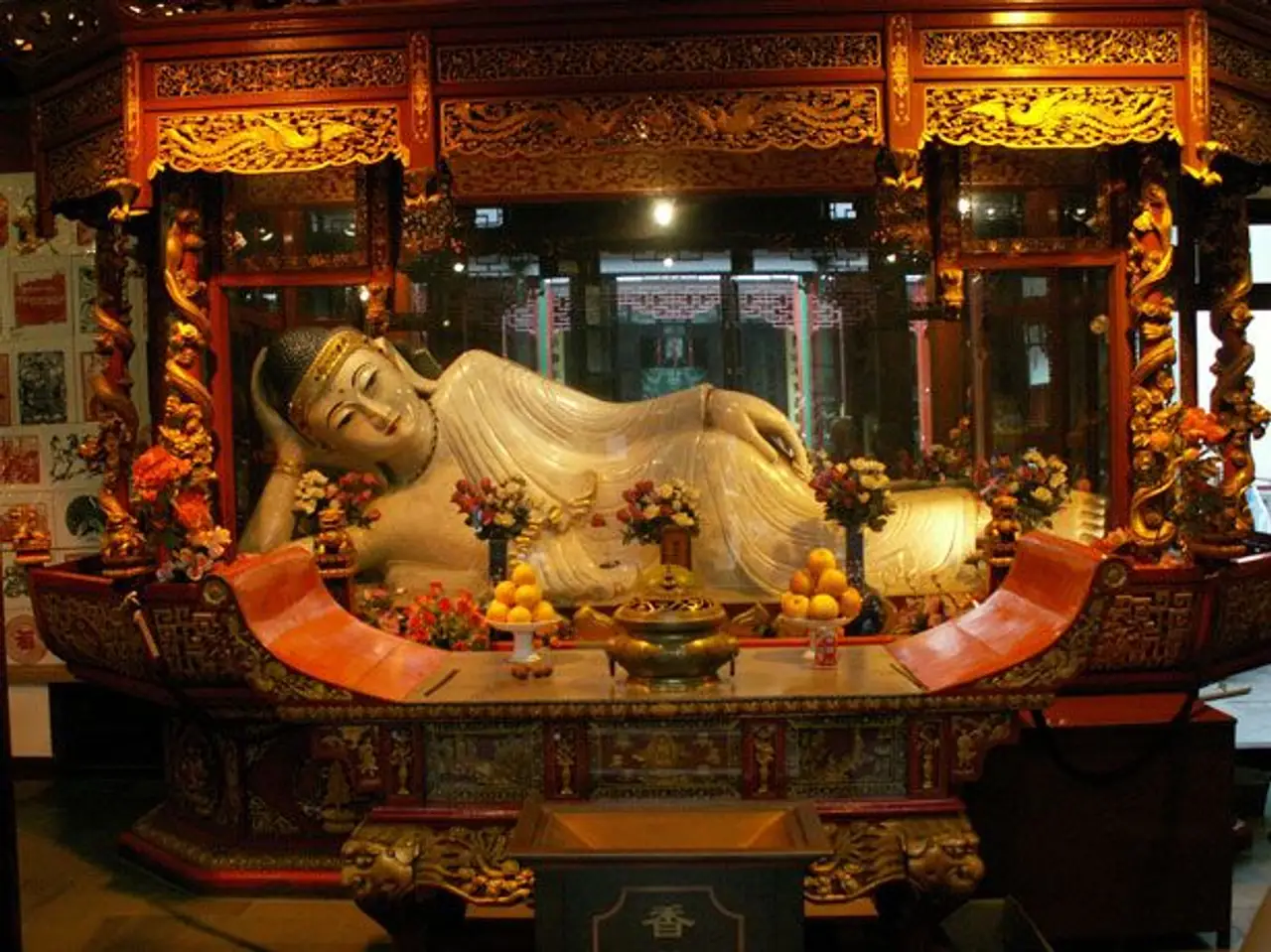 Une statue traditionnelle de Bouddha allongé en jade blanc précieux reposant sur un autel en bois sculpté et doré dans un temple à Shanghai.