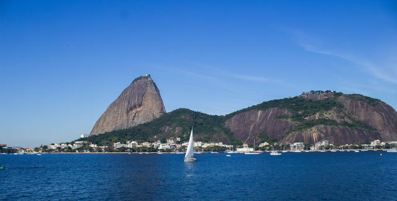 Voyage au Brésil – Vue depuis les eaux de la baie de Guanabara sur le pic rocheux du Pain de Sucre sous un ciel bleu à Rio de Janeiro.