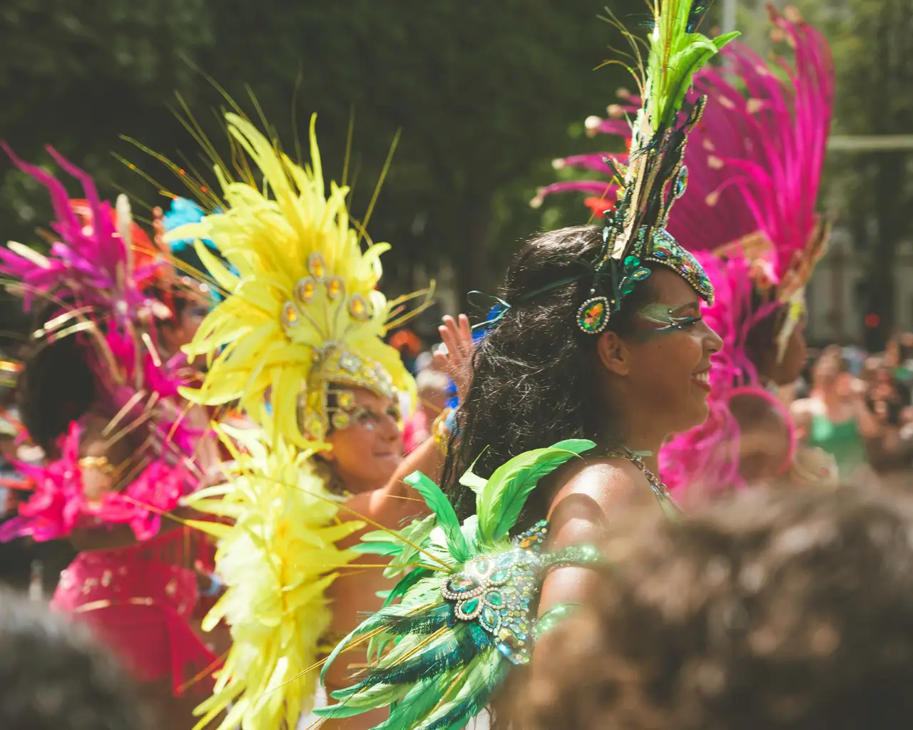 Voyage au Brésil – Des danseuses costumées portant des coiffes de plumes colorées jaunes et roses lors d'une immersion dans une école de samba à Rio de Janeiro.