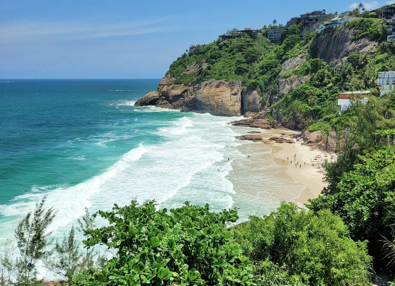 Voyage au Brésil – Petite plage de sable blanc sauvage et vagues de l'océan Atlantique bordées par les collines verdoyantes de la forêt tropicale à Rio de Janeiro.