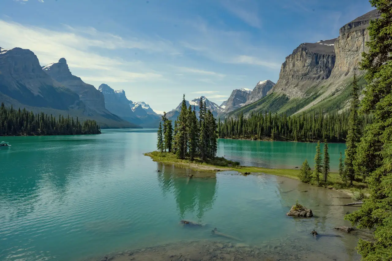 Spirit Island bordée de pins au milieu des eaux turquoise du lac Maligne entouré de sommets alpins dans le parc national de Jasper