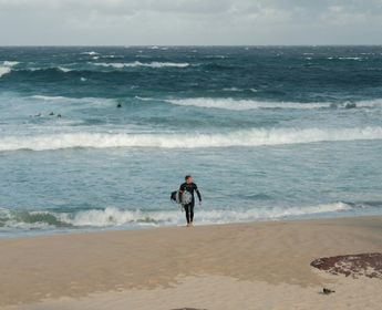 Surfeur sortant de l'eau avec sa planche sur la plage de Bondi