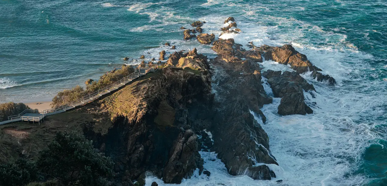 Sentier de bois sinuant le long des falaises escarpées de Byron Bay