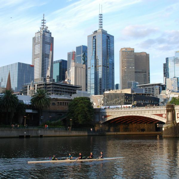Équipe d'aviron glissant sur les eaux calmes de la rivière Yarra avec les gratte-ciel de Melbourne en arrière-plan