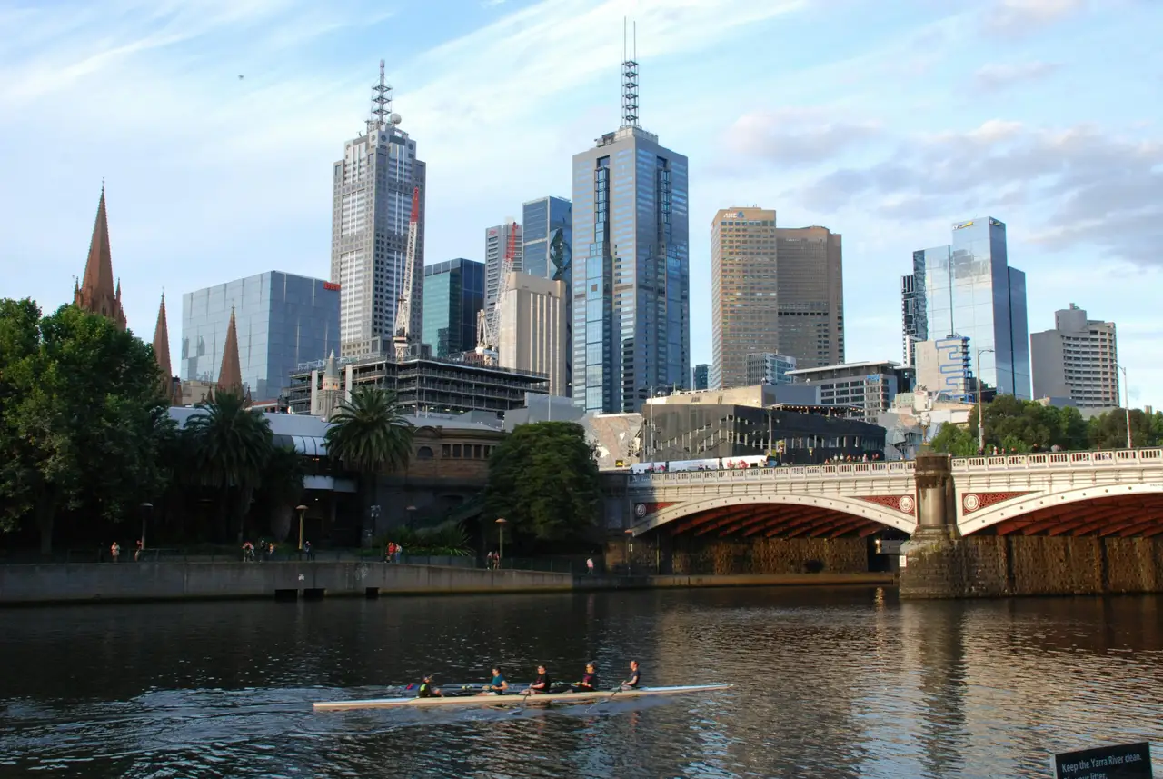 Équipe d'aviron glissant sur les eaux calmes de la rivière Yarra avec les gratte-ciel de Melbourne en arrière-plan