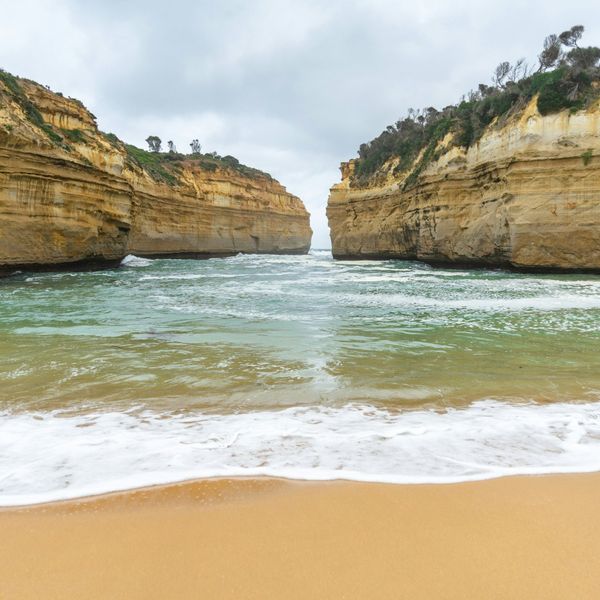 Vagues de l'océan s'engouffrant entre les falaises dorées de Loch Ard Gorge sur la Great Ocean Road