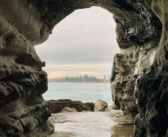 Grotte rocheuse s'ouvrant sur les eaux claires et les surfeurs au large de Manly Beach
