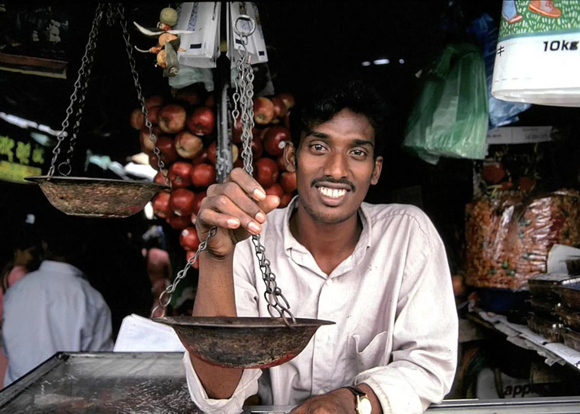 Commerçant sri lankais souriant avec une balance traditionnelle sur un marché