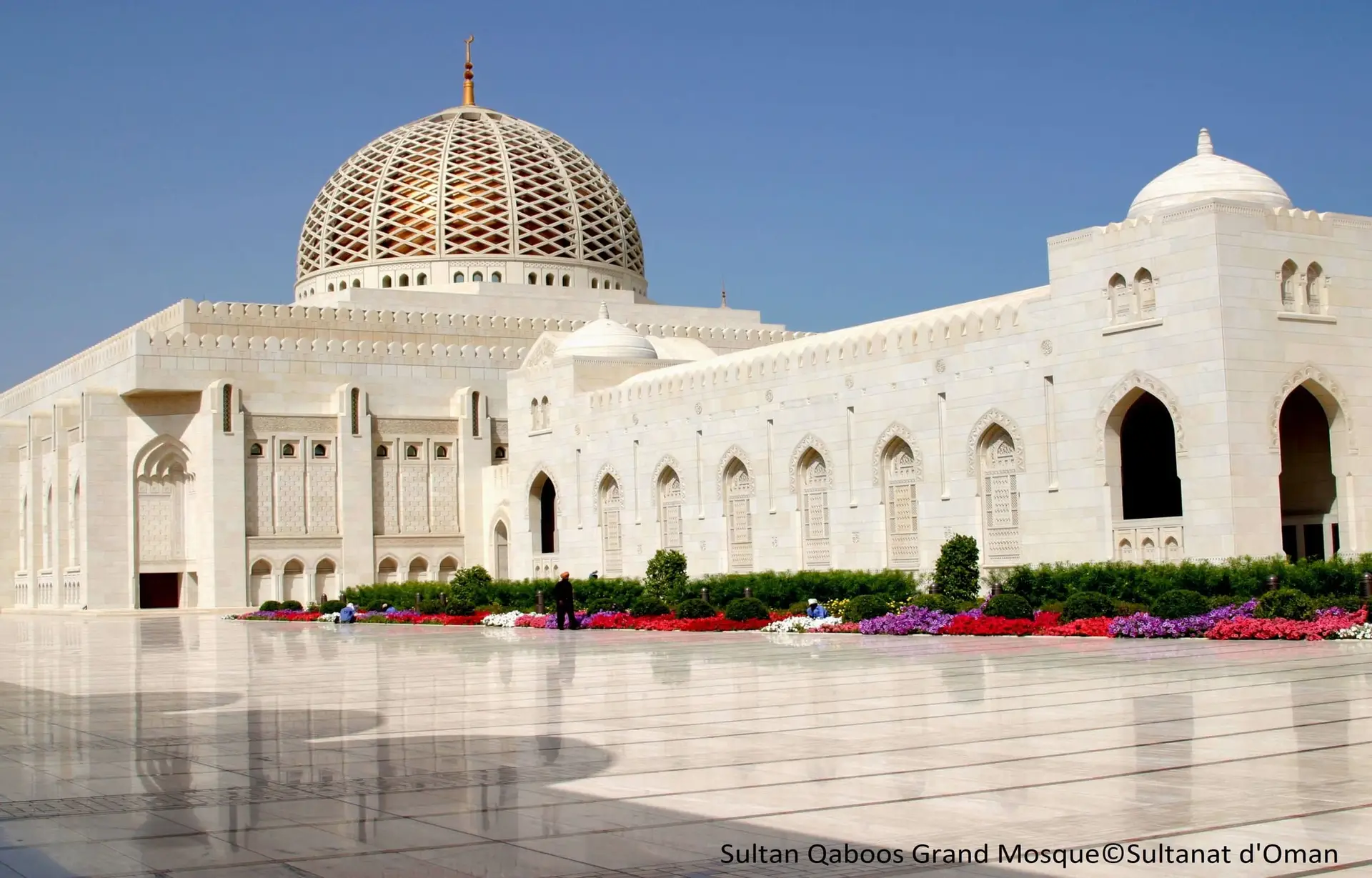 Architecture majestueuse de la Grande Mosquée du Sultan Qaboos à Mascate, avec son dôme doré et ses minarets.