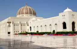 Architecture majestueuse de la Grande Mosquée du Sultan Qaboos à Mascate, avec son dôme doré et ses minarets.