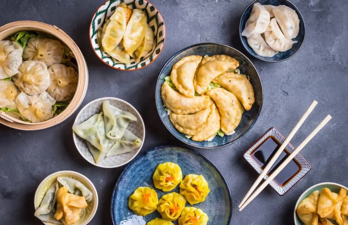 Assortiment de dim sum traditionnels chinois incluant des raviolis vapeur et des siu mai servis dans des bols sur une table.