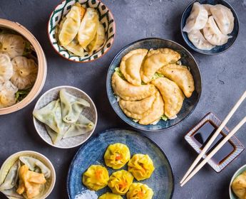 Assortiment de dim sum traditionnels chinois incluant des raviolis vapeur et des siu mai servis dans des bols sur une table.