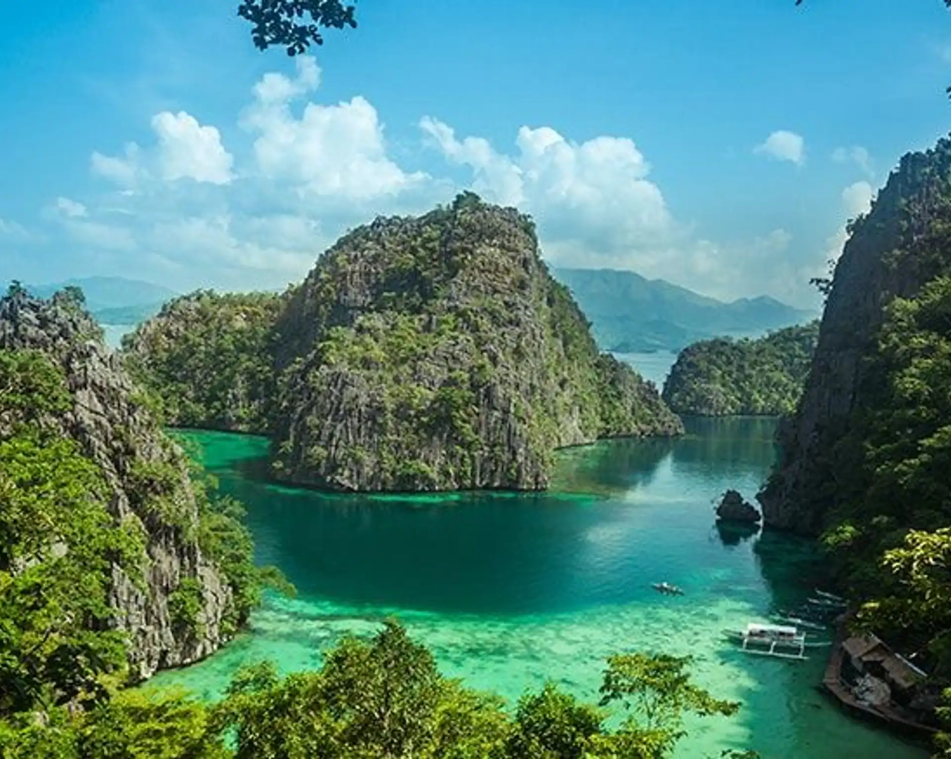 Paysage tropical de Coron aux Philippines montrant des falaises karstiques verdoyantes entourant des eaux turquoise.
