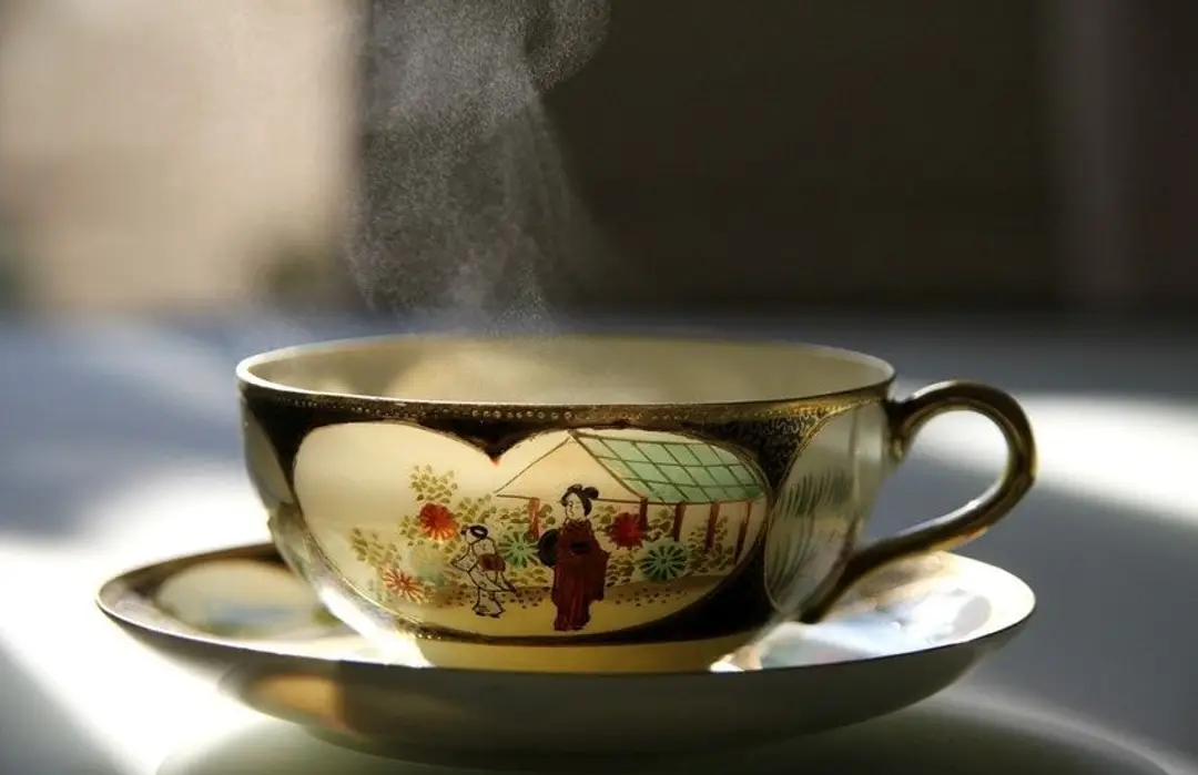 Route du thé au Japon – Tasse en porcelaine Satsuma délicatement ornée fumante d'un thé chaud.